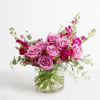 All-around arrangement of lavender roses, fuchsia stock, purple waxflowers, pink statice, and