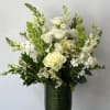 Seasonal white flowers arranged with fillers and greens in a vase.