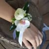 Wrist corsage with white cymbidium orchid and white ranunculus as shown in