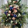 A standing spray of larkspur, stock, iris, roses, mini carns, daisies, palm