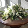 beautiful all white casket cover with hydrangeas, roses, snap, stock, bells of