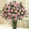 Dozen pink roses in a clear vase with beautiful greens. This is
