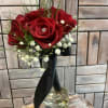 A classic red rose and baby&#039;s breath bouquet hand tied with ribbon.