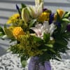 Pink Lilies, Yellow roses daisies, iris, purple carnations and solidago arranged in