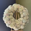 This graceful all-white standing wreath is a timeless expression of peace and