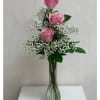 Three Pink roses in a bud vase arranged with greens and filler.