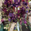 A beautiful European-style wreath in a heart shape with assorted purple flowers.

