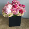 Lush peonies, cymbidium orchids, hydrangeas flowing over the edges of a black