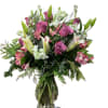 Arrangement featuring Lilies and long stem lavender roses designed in tall clear