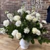 White urn filled with dark green mixed foliages, fragrant stocks, carnations and