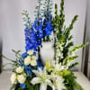 The Blue and White Urn Surround is an elegant floral arrangement featuring