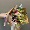 Wrapped bouquet of white roses, lisianthus, stock and lilies. Please note this