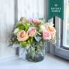 A soft and inviting arrangement featuring peach and blush roses, green hydrangea