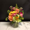 A bright seasonal arrangement, with a variety of blooms in citrus inspired