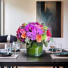 A bold and colorful arrangement featuring fuchsia Phalaenopsis orchids, orange and hot