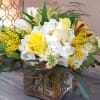 Bright display of yellow and white flowers arranged in a low, glass