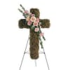 Cross on a stand covered with moss with a cluster of carnations