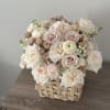 A charming arrangement of soft blush and ivory roses, delicate ranunculus, and