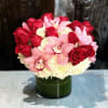 Roses, Hydrangeas, and Cymbidium Orchids in a glass vase. 