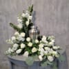 This urn arrangement has roses, stock, silver dollar eucalyptus, spiral eucalyptus and