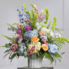 A graceful spring-inspired basket featuring soft hydrangeas, roses, lisianthus, and bells of