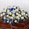 Half casket arrangement with white and blue shades with a beautiful bow