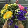 This beautifully creative arrangement includes roses, sunflowers, yellow solidago, white and green