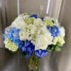 White and blue hydrangeas and white roses in vase with bow