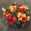 A short and full arrangement made with red and gold flowers. 