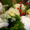 A holiday arrangement that includes a combo of green textures, red flowers