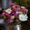 An assortment of spray garden roses with another neutral colored flower in