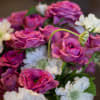 An assortment of spray garden roses with another neutral colored flower in