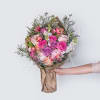 A gorgeous wrapped bouquet designed with lush premium roses, stock, tulips, and