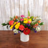 Beautiful bright and colorful floral arrangement comes in a white tin with