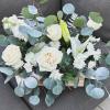 White roses, white chrysanthemums, white lilies, eucalyptus, and greenery, arranged in a