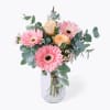 A delicate blend of soft pink Gerbera daisies and warm peach roses