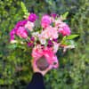 This floral gift is arranged in shades of pink, purple, and white