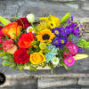 A fun colorful low arrangement designed in a wide ceramic vase in
