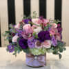 A variety of beautiful purple and pink flowers in a vase covered