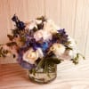 Sumptuous collection of blue delphinium, hydrangea, white ranunculus and white roses. 