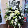 Standing spray in white and black flowers with a 24&quot; Raiders wood