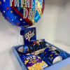 A blue wooden tray includes a balloon and assorted items similar to