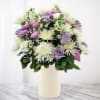 A beautiful collection of lavender and white flowers in a white vase.
