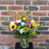 A bouquet bursting with an array of wildflower-themed blooms...Bright sunflowers, orange snapdragons
