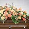In a symphony of warmth and grace, this casket spray captivates with