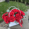A stunning arrangement of fresh red roses in an elegant white handbag.