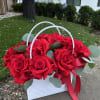 A stunning arrangement of fresh red roses in an elegant white handbag.