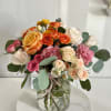 A charming mix of roses in warm tones, lilac carnations, and eucalyptus