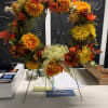 Fall colored silk flowers on a grapevine wreath, with a tripod for