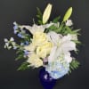 This peaceful arrangement includes roses, oriental lilies, fuji mums, blue delphinium, blue